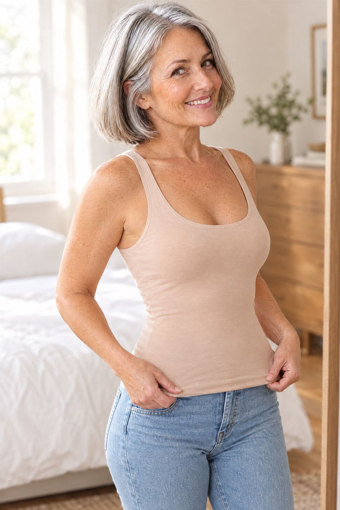 Woman in her bedroom smoothing the tank down over her hips