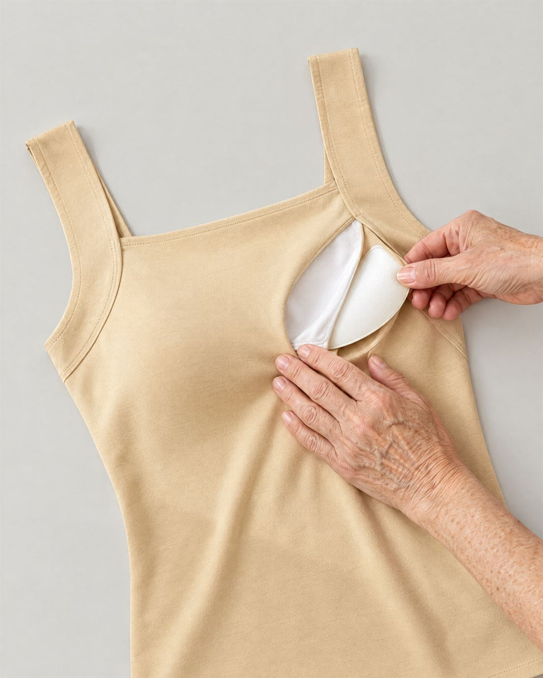 The tank laid flat, with hands sliding a soft removable pad out of its inner pocket