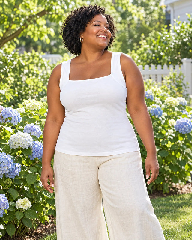Curvy woman laughing in a sunny garden in the White bra tank