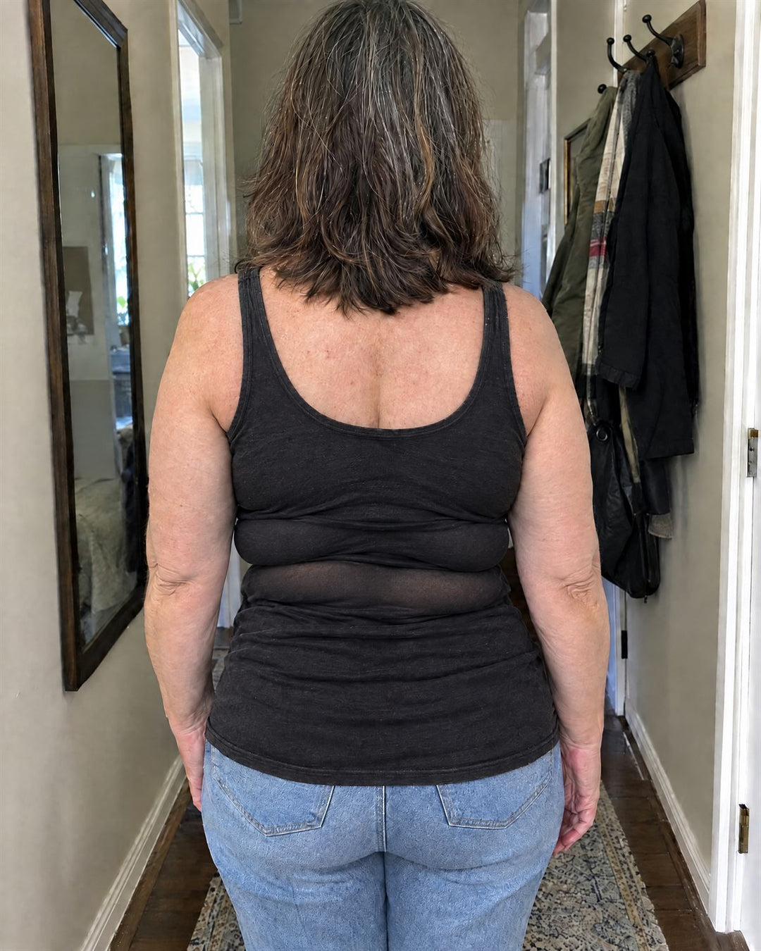 The same woman in an old black tank that bunches and shows rolls across her back